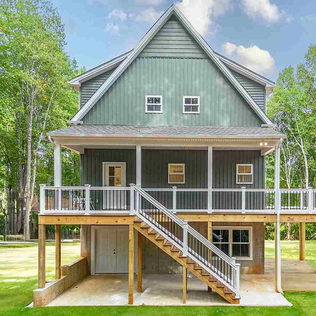 Green house exterior with white trim balcony and wooden stairs