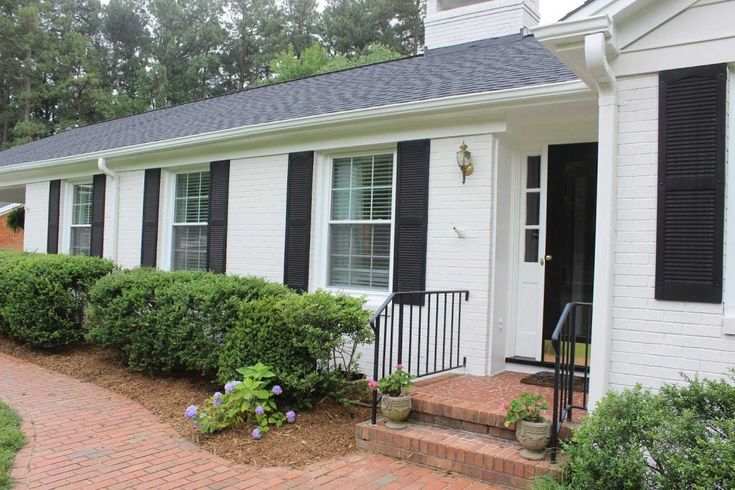 White house with black shutters and light on the wall