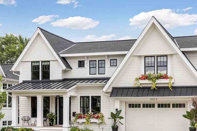 A white house with black roof and glass windows and white garage door 