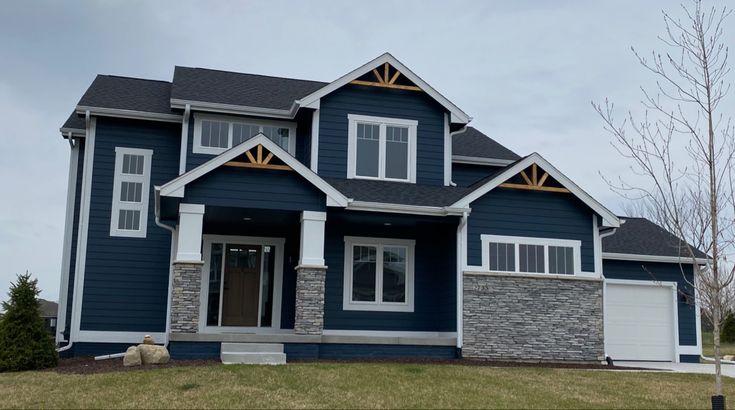 Dark blue house with white trim and stone and white pillars