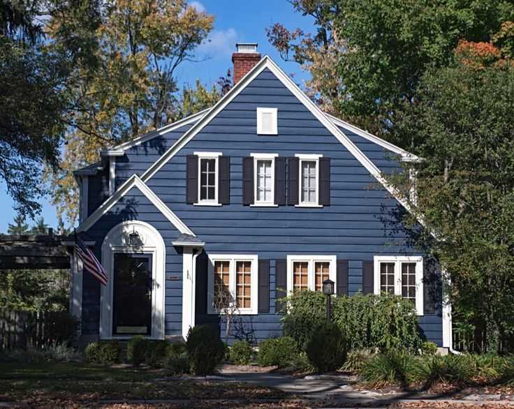Dark blue house with white trim and black shutter and garden outside of the house