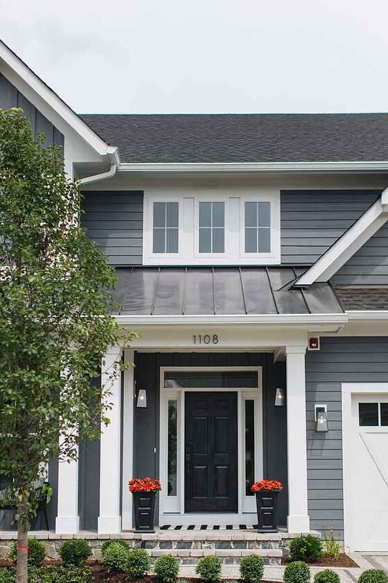 Dark grey front door on light grey house light on the both wall 