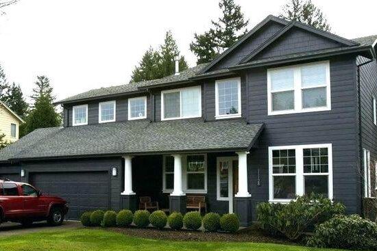 A grey house with white trim and garden outside of the house 
