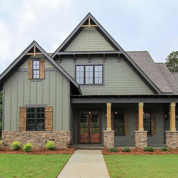A green house with wooden and stone base pillars and black windows