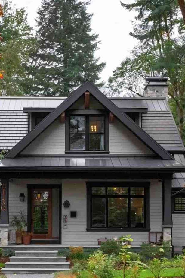 A grey house with black glass windows and wooden door
