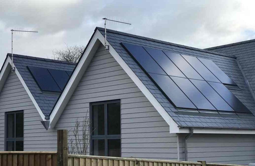 A grey house with black roof and trim and solar panels 