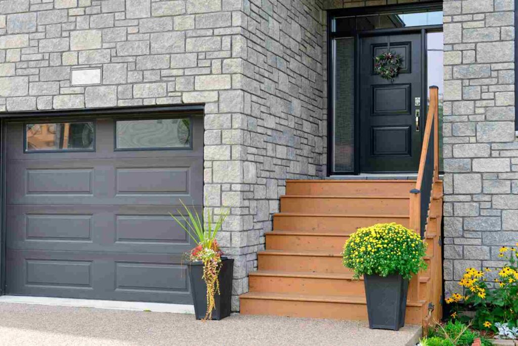 Stone house with black wooden door and wooden stair and railing 