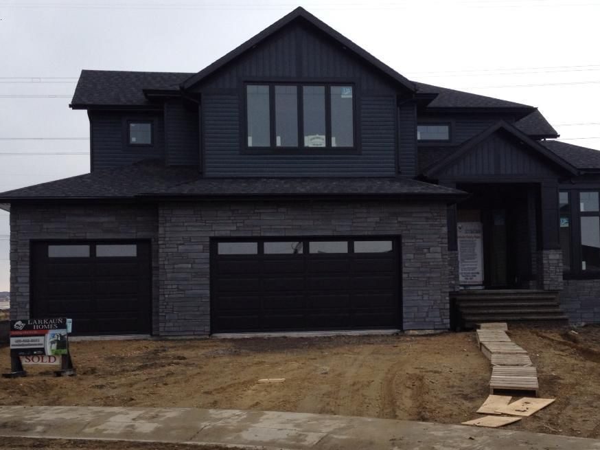 Dark grey house with black trim windows and stone pathway 