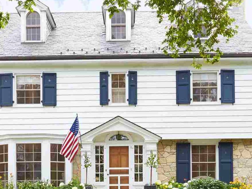 A white house with blue shutters and wooden door