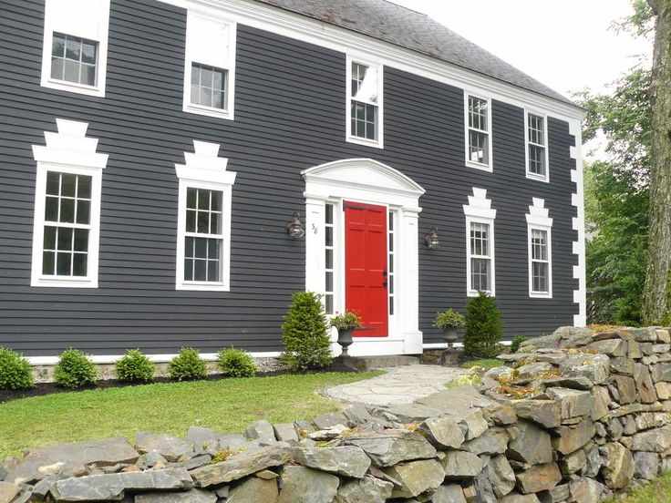 Red door on grey house with white trim and garden outside of the house 