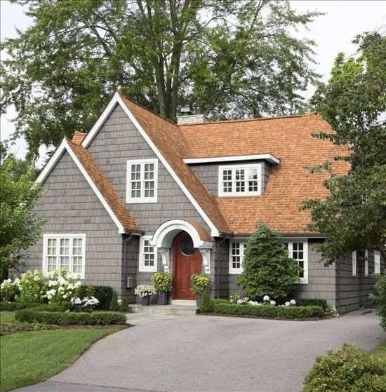 Light grey siding with brown roof and windows and garden outside of the house 