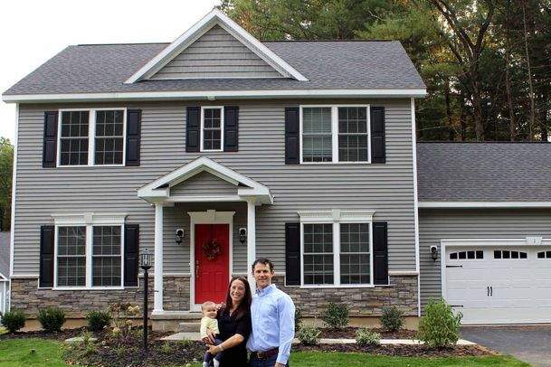 A grey house with shutter and red door 
