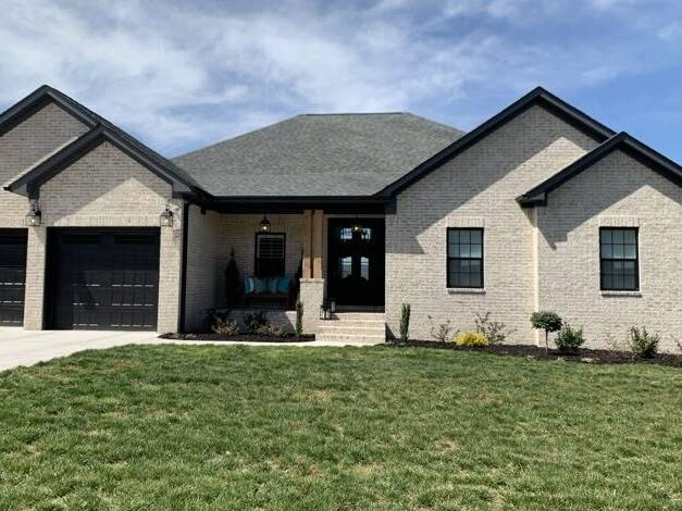 Beige house with black trim and black windows and garden outside of the house