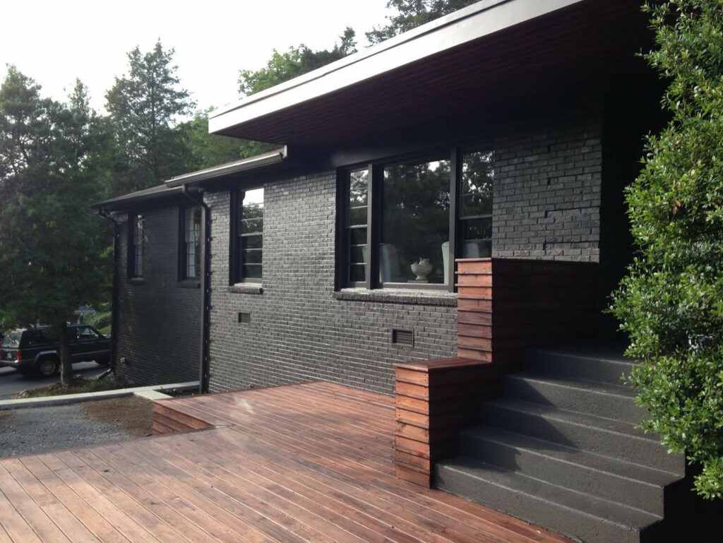 Black brick house with black trim windows and wooden deck 