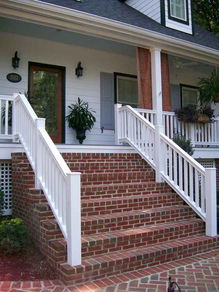 Modern white facade with red brick stairs and white railing and lamp on the wall