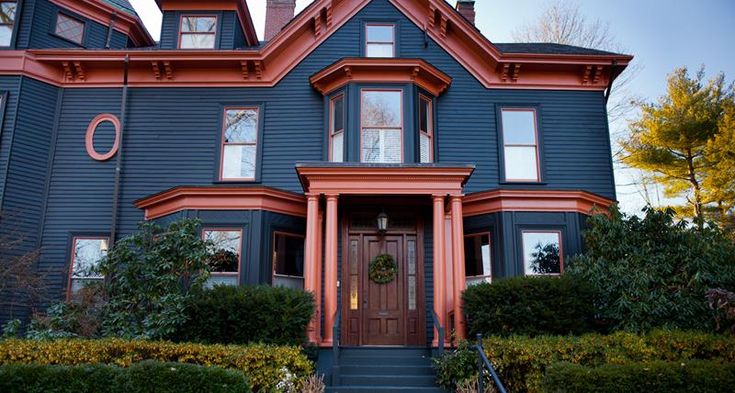 A blue house with red trim and glass windows and wooden door