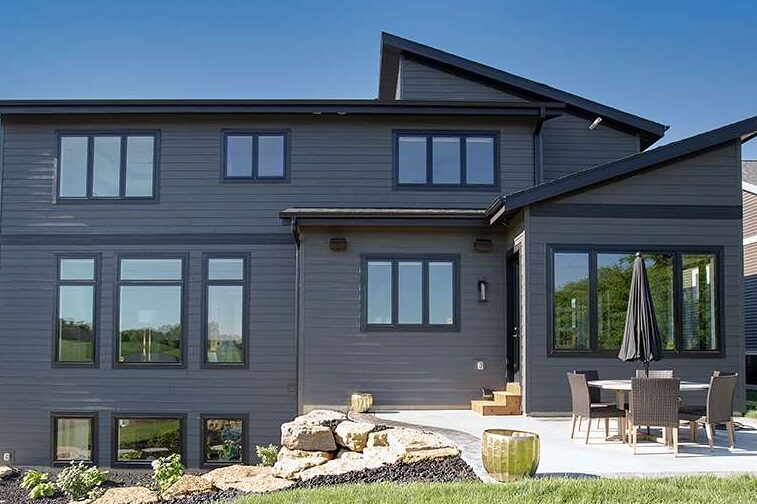 Navy blue house with black trim and black windows and chairs and table outside of the house