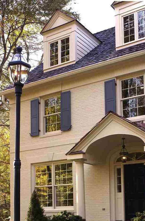 Off-white brick house with dark blue windows and shutters