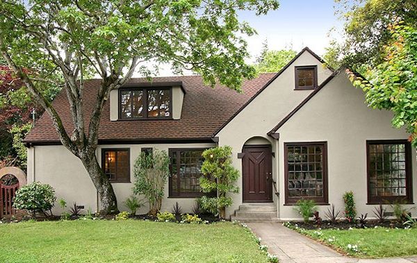 Off white house with brown trim windows and garden outside of the house
