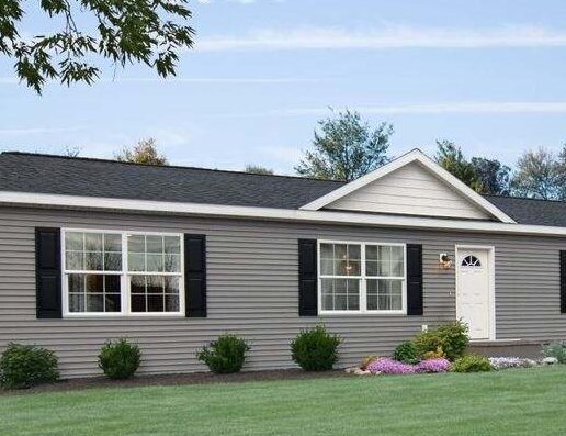 A tan house with black shutter and white front door and garden outside of the house