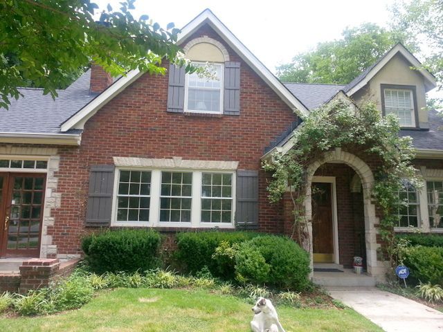 Red brick house with windows and greyl trim and plants outside of the house