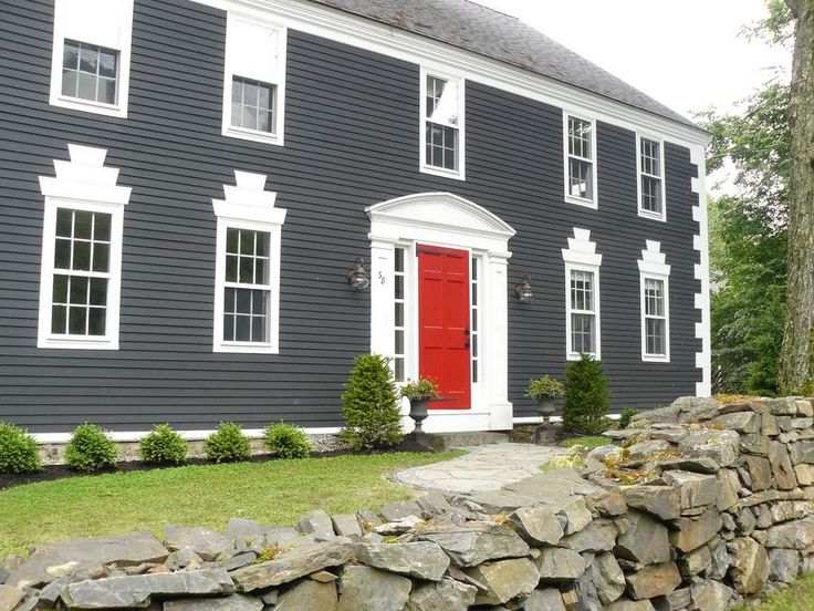 A grey house with red door and white trim windows 