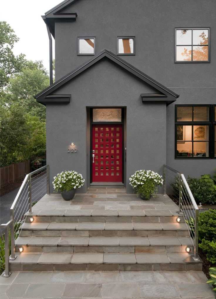 A red door on gre y house with glass window