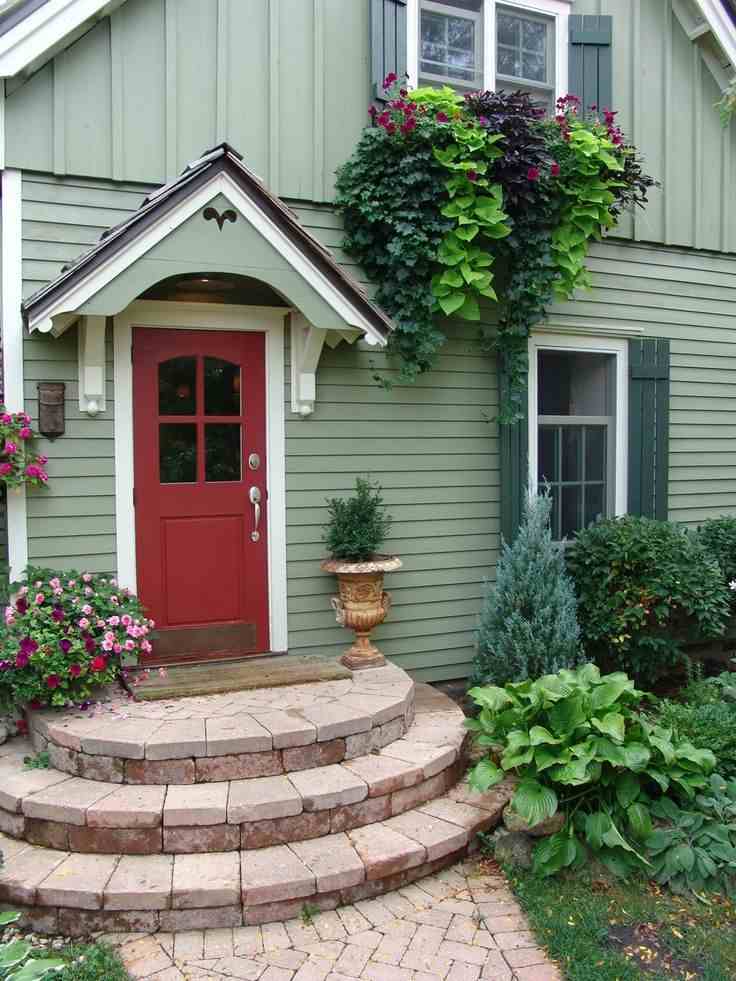 A green house with red door and stone stairs 