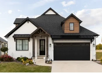 A white house with black front door and roof and wooden garage door