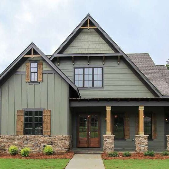 A green house with stone base pillars and glass windows and wooden shutter 