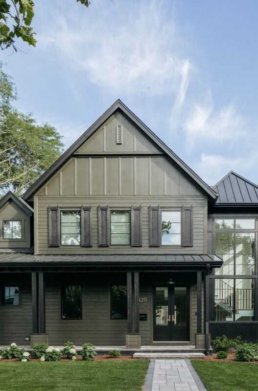 Green house with black windows and shutter and glass door and pillars