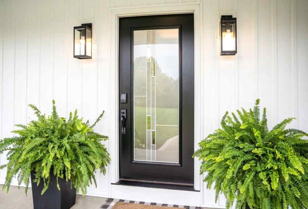 White house with Black front door glass and lights on the wall
