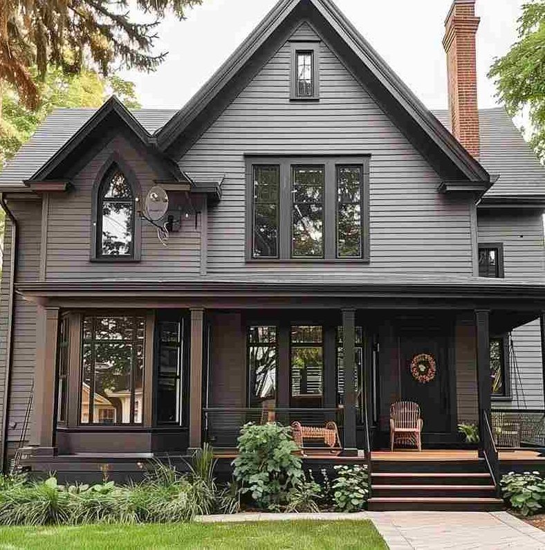 Stone chimney on light grey house and dark grey trim and chair outside of the house 