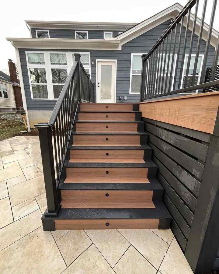 grey house with stairs and black railing and white trim and glass windows 