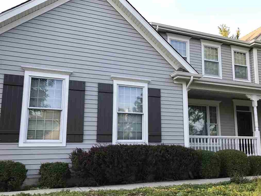 Light grey house  with dark grey shutters and white trim windows 