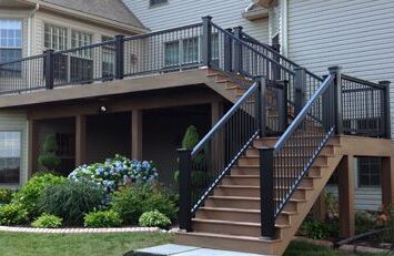 Tan house with black railing and garden outside of the house
