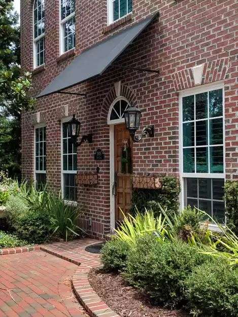 Two-story red brick house with metal black awning and white framed windows
