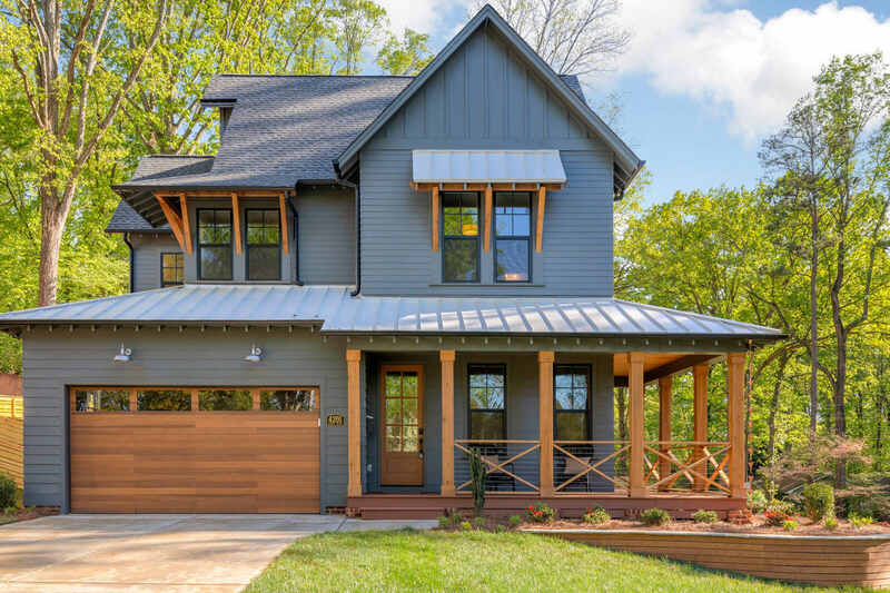 A grey house with wooden trim and glass windows 