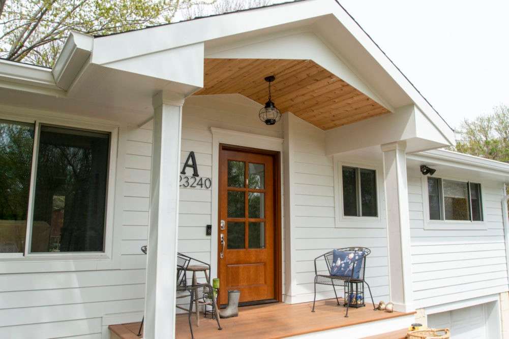 A white house board and bitten and wooden deck and wooden door and white pillars