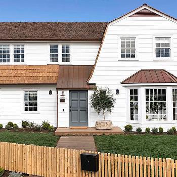 A house with brown roof and white framed windows and grey door and garden outside of the house