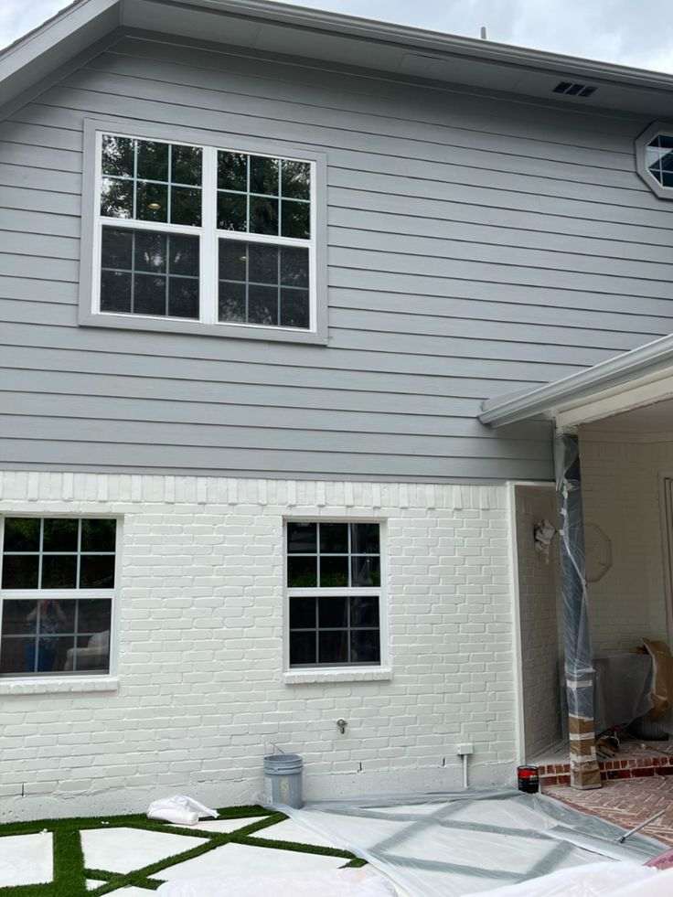 White brick house with grey siding and white trim windows