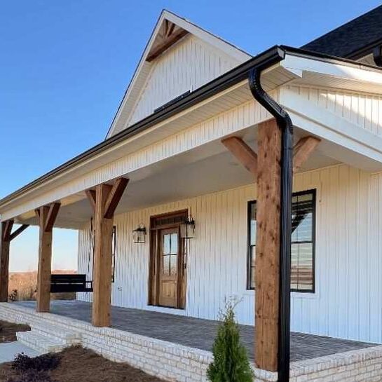 A white house with wooden pillars and black trim windows