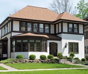 A white house with brown trim and brown windows and garden outside of the house