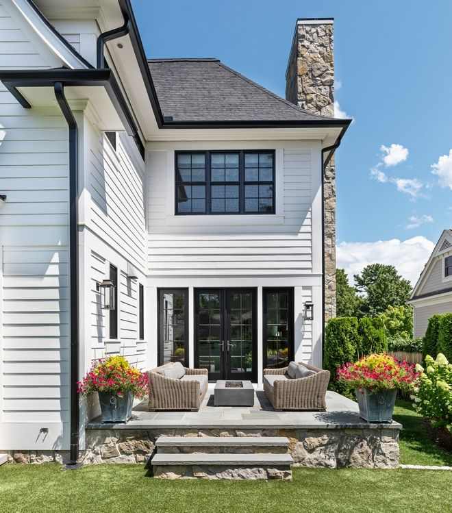 A white house with black and black windows and sofa and table outside of the house