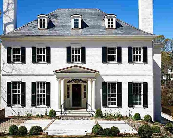 A white house with black shutter and stone pathway and white trim windows