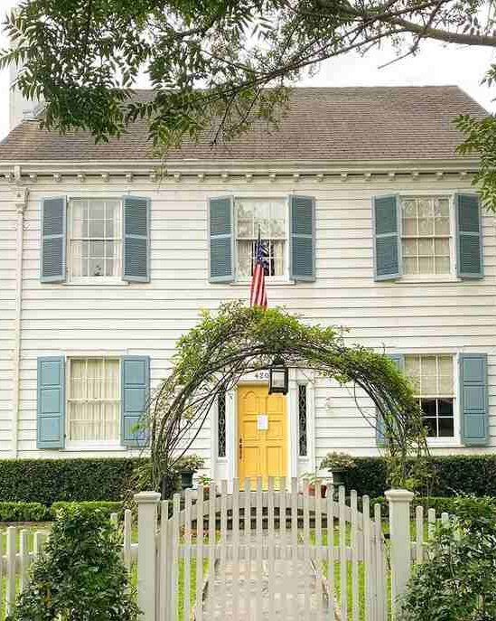 White house with blue shutter and yellow door