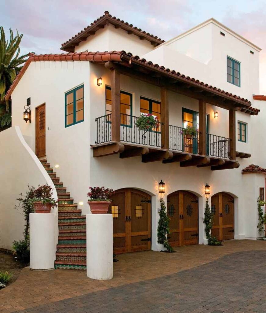 A white house with brown balcony and lights on the wall