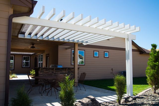 A tan house with white pergola and white trim windows