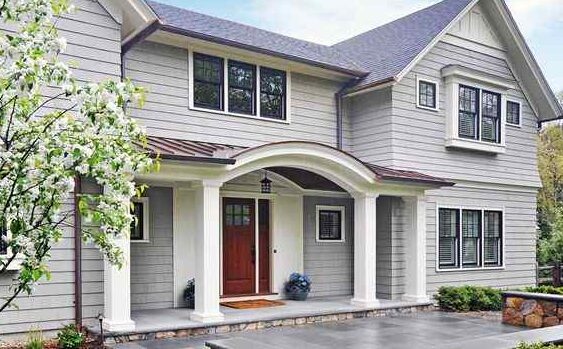 Light grey house with white porch and red door and black trim windows