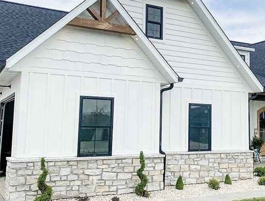 A natural stone house with white house and black glass windows and a gable roof